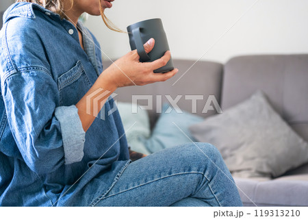 Woman enjoying coffee in cozy living room setting. 119313210