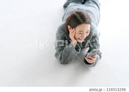 床に寝転びスマホを操作する女性 床に寝転びスマホを操作する女性 119313298