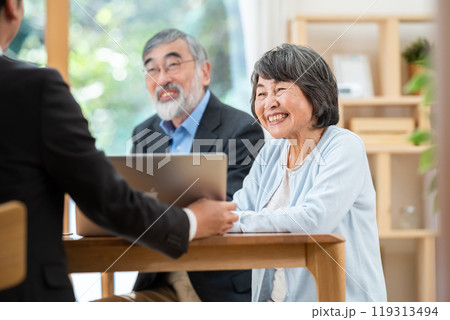 シニア夫婦に説明する営業マン 119313494