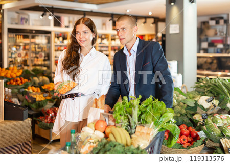 Portrait of a happy young couple in a supermarket with a full grocery cart 119313576