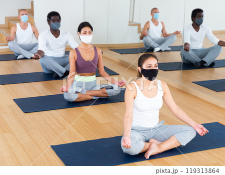 Young people meditating together at yoga class 119313864
