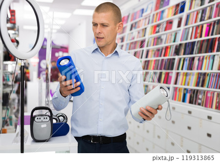 Male customer choosing boombox in consumer electronics store 119313865