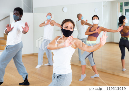 Woman in protective mask enjoying active dancing during group training Woman in protective mask enjoying active dancing during group training 119313919