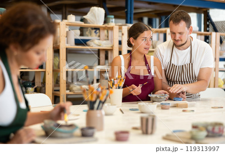 During master class, student paints clay vessel under guidance of male teacher. During master class, student paints clay vessel under guidance of male teacher. 119313997