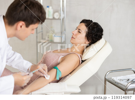 Male anesthesiologist injecting anesthetic into vein on her arm with syringe in cosmetology clinic 119314097