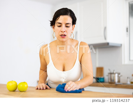 Young Chilean woman wiping dust from kitchen table Young Chilean woman wiping dust from kitchen table 119314237