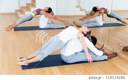 Women and men exercising in pairs during yoga class in fitness center Women and men exercising in pairs during yoga class in fitness center 119314280
