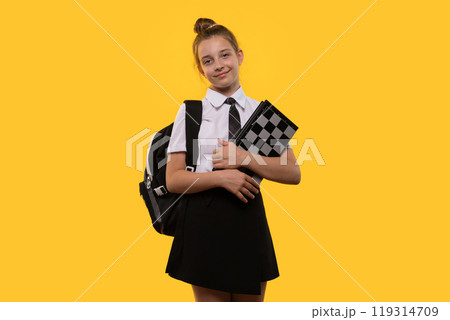 Schoolgirl poses with chessboard, showing readiness to play. 119314709