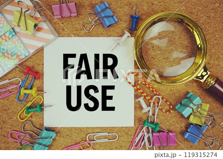 Fair Use text on paper card with magnifying glass and stationery on cork board background Fair Use text on paper card with magnifying glass and stationery on cork board background 119315274