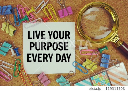 Live Your Purpose Every Day text on paper card with magnifying glass and stationery on cork board background Live Your Purpose Every Day text on paper card with magnifying glass and stationery on cork board background 119315308