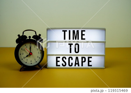 Time to Escape text on LED lightbox with alarm clock on yellow background 119315469