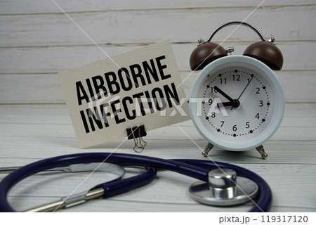 Airborne Infection text message on paper card with stethoscope and alarm clock on wooden background 119317120