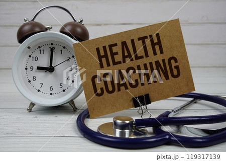 Health Coaching text message on paper card with stethoscope and alarm clock on wooden background Health Coaching text message on paper card with stethoscope and alarm clock on wooden background 119317139