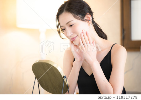 黄色いダウンライトで寝る前の肌のスキンケアをする女性 119317279