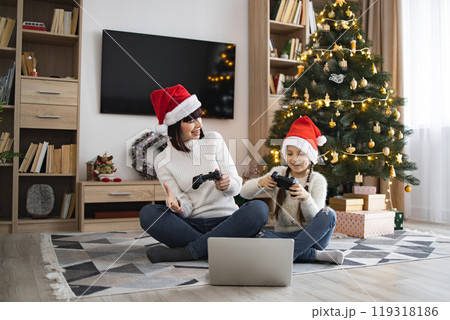 Mother and daughter joyfully play video games during Christmas Mother and daughter joyfully play video games during Christmas 119318186