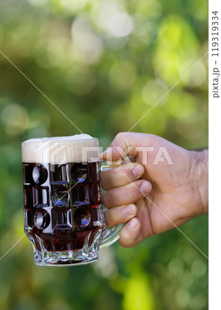 closeup male hand with mug of dark beer closeup male hand with mug of dark beer 119319334