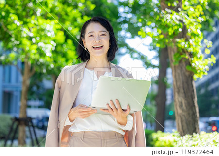 外でパソコンを持つ女性　ビジネス 119322464