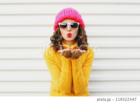 Fashion cool girl blowing red lips kiss, colorful knitted yellow sweater hat on white background 119322547