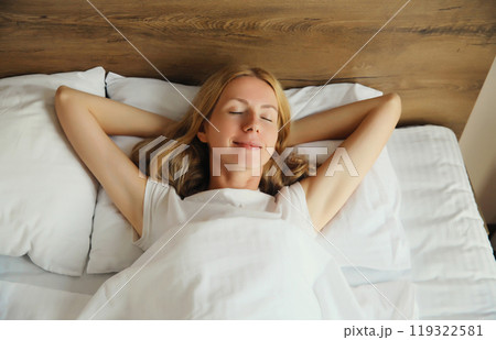 Woman sleeping lying in bed on white soft comfortable pillow in bedroom at home 119322581