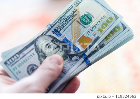 left hand holding stack of us dollar banknotes 119324662
