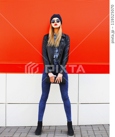 Stylish beautiful blonde woman model posing in black rock style with handbag clutch in the city Stylish beautiful blonde woman model posing in black rock style with handbag clutch in the city 119325070