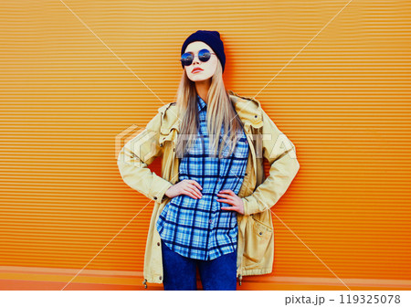 Fashion portrait blonde woman in black sunglasses and hat on a colorful orange background Fashion portrait blonde woman in black sunglasses and hat on a colorful orange background 119325078