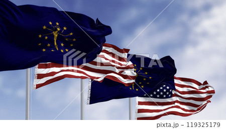 Indiana state flags waving with the national flag of the US on a clear day 119325179