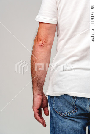 A close-up view of a man's bare hand resting against his side 119325199