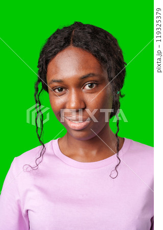 Young woman with curly hair shows a skeptical expression against a bright green background Young woman with curly hair shows a skeptical expression against a bright green background 119325379
