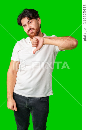 A man expresses disappointment with a thumbs down gesture against a bright green background 119325458