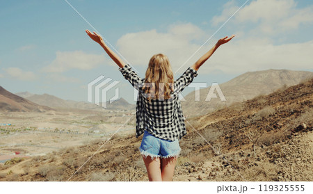 Happy woman raises hands up on hiking trail on top of mountain, Tenerife, Canary Islands, Spain 119325555