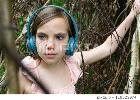 Girl around with a branch and wearing headphones Girl around with a branch and wearing headphones 119325974