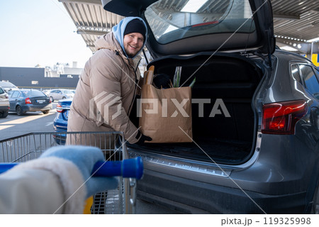 Man Loading Groceries into Car Trunk 119325998