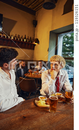 Man focused, and intensely listening his coworker, his colleague talks to him over drinks, snacks in cozy bar setting. 119326151