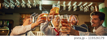 Close-up of four hands raising their glasses in toast, emphasizing unity and celebration in festive bar setting. Friday mood. Close-up of four hands raising their glasses in toast, emphasizing unity and celebration in festive bar setting. Friday mood. 119326179