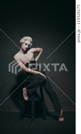 Portrait of young man elegantly leaning on chair, lends historical poise with modern calm, creating balance between art and fashion. Portrait of young man elegantly leaning on chair, lends historical poise with modern calm, creating balance between art and fashion. 119326275