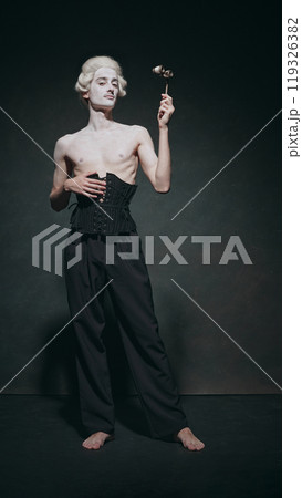 Pale man stands with dramatic posture, holding opera glass, and nod that classic elegance mixed with modern minimalism. 119326382