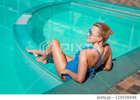 Bikini-clad woman enjoys poolside relaxation. Poolside ambiance. Capturing woman's relaxed time near pool. Bikini-clad woman enjoys poolside relaxation. Poolside ambiance. Capturing woman's relaxed time near pool. 119326846