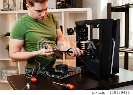 Man assembles a computer system unit at home Man assembles a computer system unit at home 119329458