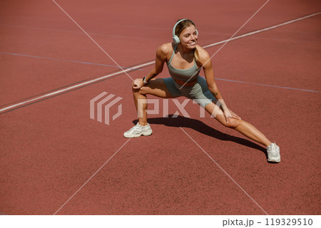 A woman stretches on a tennis court in headphones, enhancing her focus and motivation A woman stretches on a tennis court in headphones, enhancing her focus and motivation 119329510