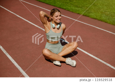 An Active Woman Happily Enjoying Her Fitness Routine on the Running Track Outdoors 119329518