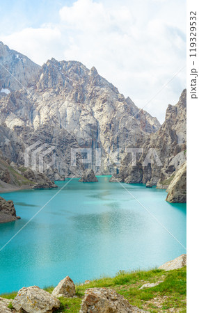 high-altitude turquoise moraine lake is located among the rocky mountains, reflecting the blue sky. The bright color of the lake contrasts with the harsh terrain,creating breathtaking Alpine landscape 119329532
