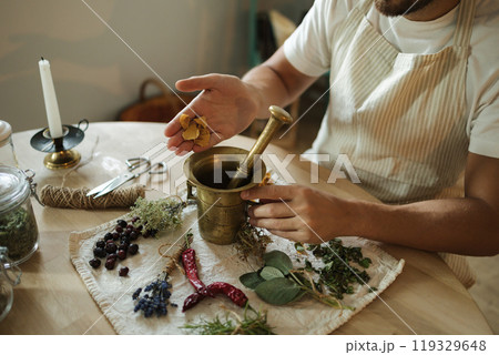 Close-up of man adds dried rose petals to a mortar and pestle. Homemade healthy and nutrition supplements Close-up of man adds dried rose petals to a mortar and pestle. Homemade healthy and nutrition supplements 119329648