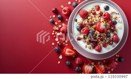 Healthy breakfast bowl with yogurt, banana, raspberries, and granola on a vibrant surface 119330997