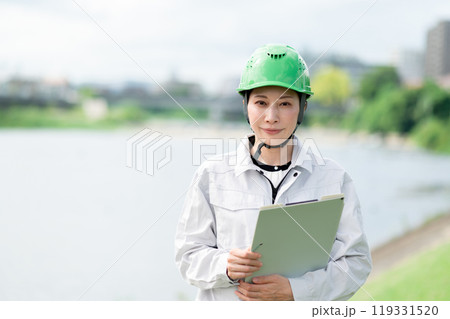 河川調査をするヘルメットをかぶった作業服姿の女性 119331520