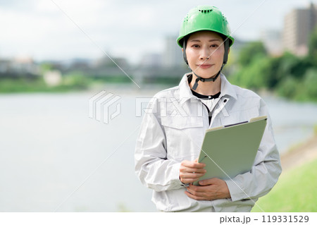 河川調査をするヘルメットをかぶった作業服姿の女性 119331529