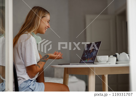 A Young Woman Actively Engaged in a Video Call at Her Cozy Home Workspace Environment 119331707
