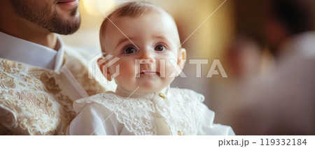 Charming baby in ornate white christening gown smiles at camera, held close to parent's embroidered attire, capturing a precious baptism moment 119332184
