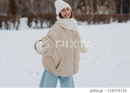 Happy smiling young woman portrait dressed coat scarf hat and mittens enjoys winter weather at snowy winter park 119334119