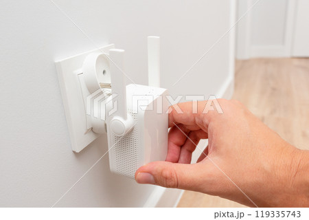 Wireless Wi-Fi repeater on white wall indoors 119335743